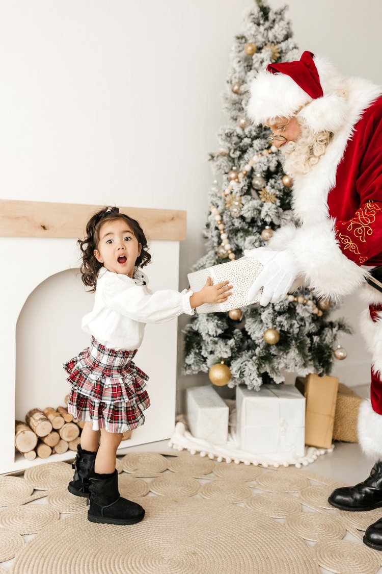 Santa Albert presenting a Christmas gift to a young child