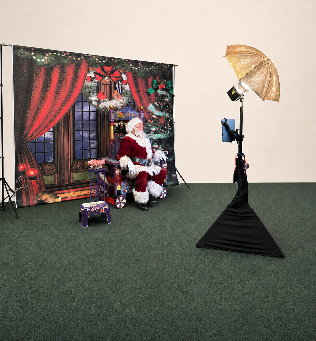 Santa Albert seated on his throne beside a professional open-air photo booth and lighting setup with a festive Christmas backdrop